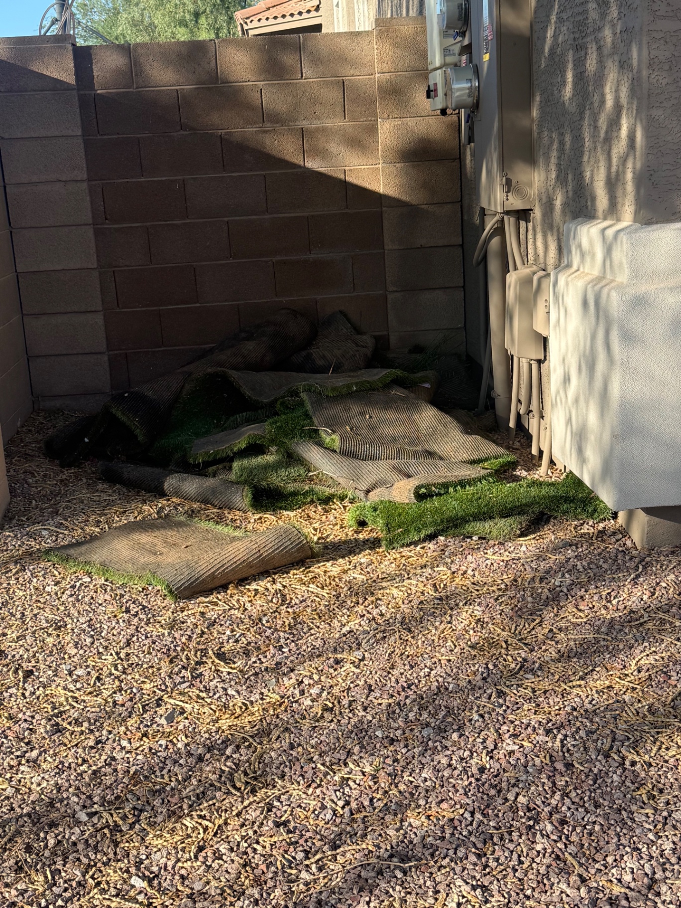 Rolled and torn artificial turf piled beside a Phoenix-area home before removal