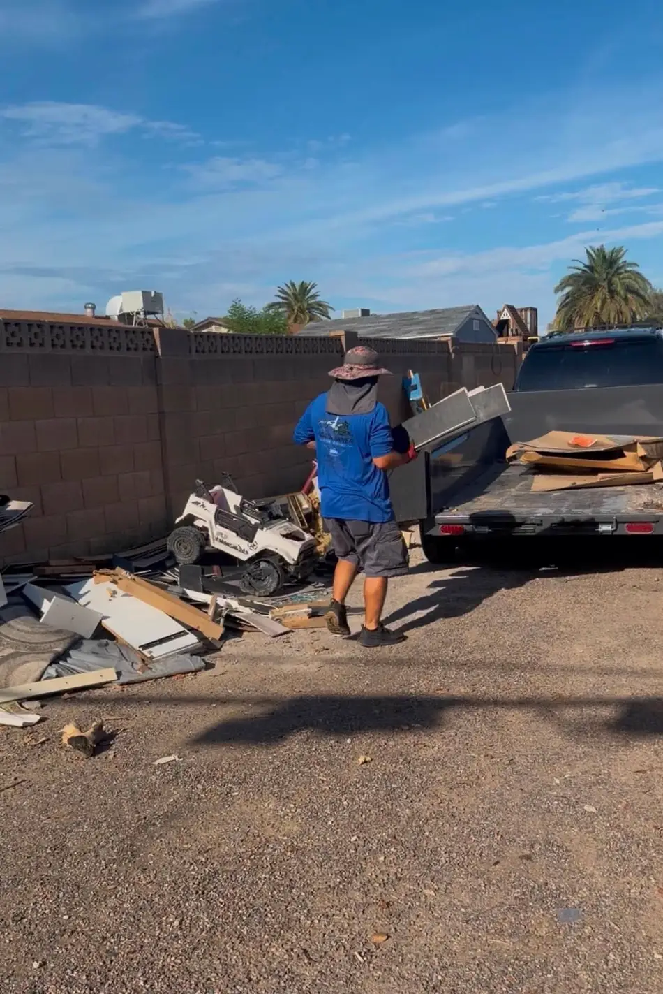 Roadrunner Junk Removal crew member in a branded shirt carrying debris to the loaded trailer