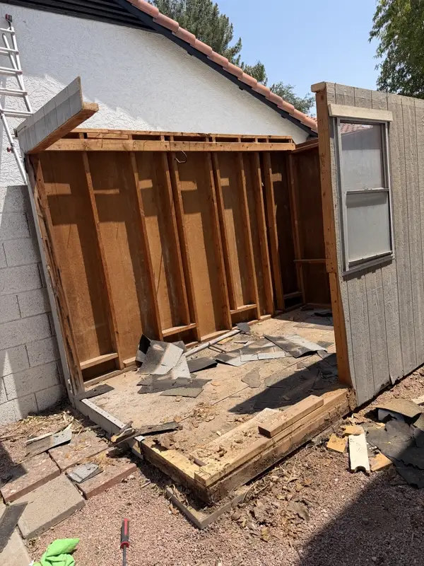 Shed stripped to bare studs with roofing debris on the floor