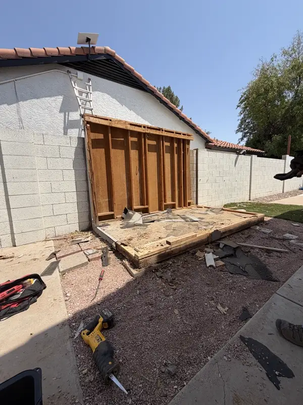 One shed wall frame left standing beside a reciprocating saw and tool bag