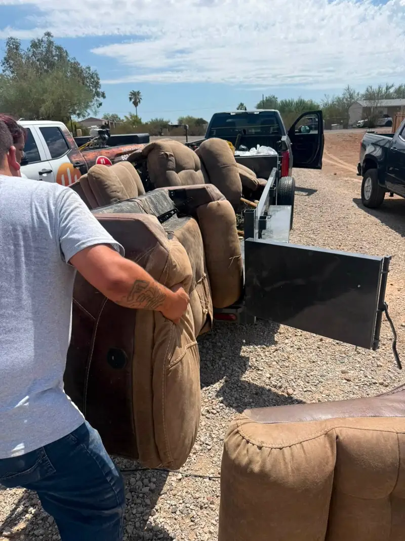 Roadrunner crew loading recliners and a sectional couch onto the trailer